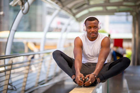 african-american man in sportswear in wireless headphones listening music and enjoying music on...