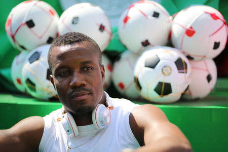 african-american man in sportswear in wireless headphones listening music and enjoying music on background of stairsの写真素材