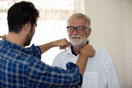 An adult hipster son and senior father spend time together at home, talking, take care father and joyful together.の写真素材