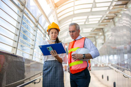 Female industrial engineer wearing a white helmet while standing in a construction site with...