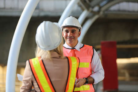 Female industrial engineer wearing a white helmet while standing in a construction site with...