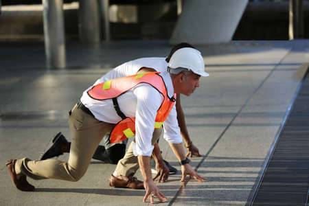 The engineer is low body in start running position with runner for the competition of successful engineering, construction, city life and future concept.の写真素材