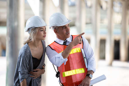 Female industrial engineer wearing a white helmet while standing in a construction site with...