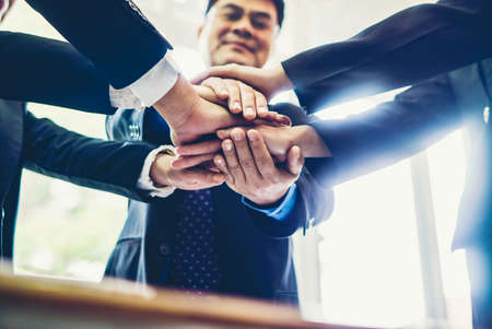 Diverse business people group put hands together in stack pile at training as concept of sales team...