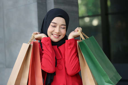 Cheerful young woman holding shopping bags.