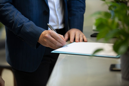 Close-up Of Businessman Signing Document On Desk In Officeの写真素材