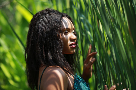 Cheerful young woman standing among tropical leaf.の写真素材