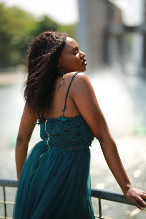 Cheerful young woman standing outdoor against water park in the garden.の写真素材