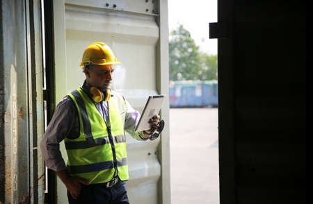 Logistics engineer control at the port, loading containers for trucks export and importing logistic conceptの写真素材
