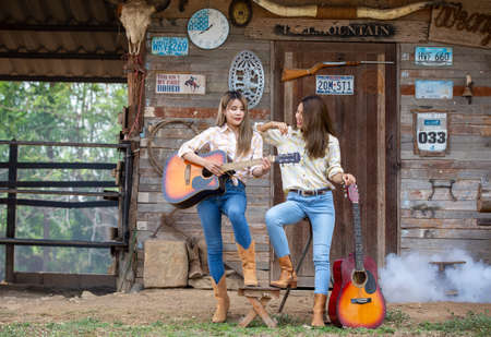 A woman in a cowgirl style sits in a horse ranch with a western farm environment.の写真素材