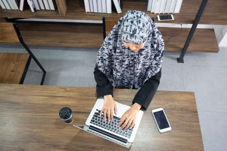 Young saudi business woman working in at home, pointing on laptop, copy space. Muslim female working with computer in the room , writing paper. Young muslim woman using laptopの写真素材