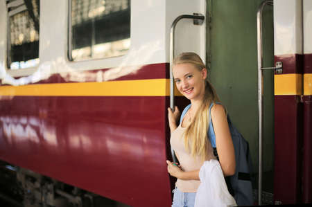young woman waiting in vintage train, relaxed and carefree at the station platform in Bangkok, Thailand before catching a train. Travel photography. Lifestyle.の写真素材