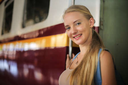young woman waiting in vintage train, relaxed and carefree at the station platform in Bangkok, Thailand before catching a train. Travel photography. Lifestyle.の写真素材