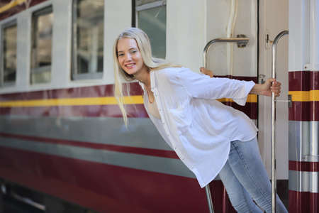 young woman waiting in vintage train, relaxed and carefree at the station platform in Bangkok, Thailand before catching a train. Travel photography. Lifestyle.の写真素材