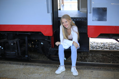 young woman waiting in vintage train, relaxed and carefree at the station platform in Bangkok,...