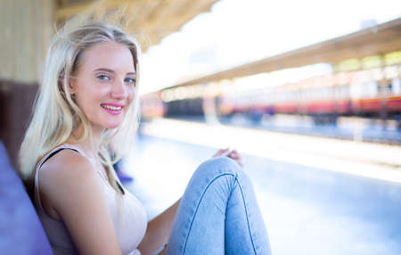 young woman waiting in vintage train, relaxed and carefree at the station platform in Bangkok,...