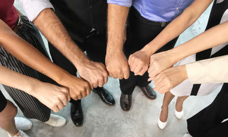 Business team showing unity with their hands together. Group of people joining hands and...