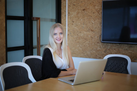 Smiling woman using laptop in work place for small businesses looking to engage audiences and scale content creation can adopt new marketing technology in workspace. Freelancer concept.の写真素材