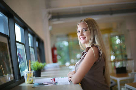 The side view of a young woman resting at the workspace at a cafÃ© indoors.