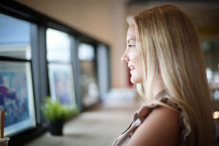 The side view of a young woman resting at the workspace at a cafÃ© indoors.