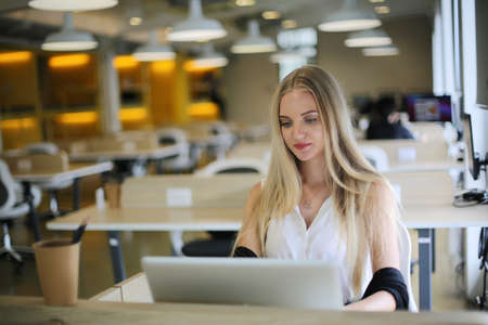 Smiling woman using laptop in work place for small businesses looking to engage audiences and scale content creation can adopt new marketing technology in workspace. Freelancer concept.の写真素材
