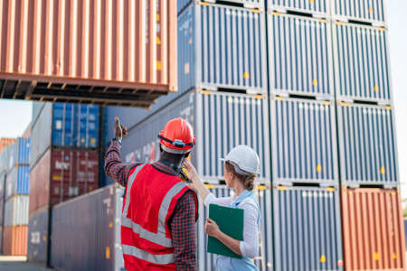 Foreman control loading Containers box from Cargo freight ship for import export. Freight containers in sea port.の写真素材