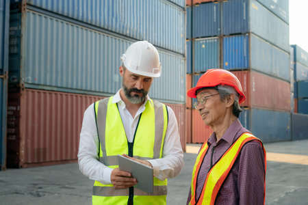 Foreman control loading Containers box from Cargo freight ship for import export. Freight containers in sea port.の写真素材