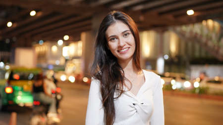 Beautiful young woman city street portrait, against bokeh light.