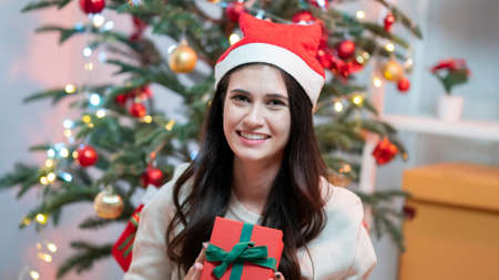 Fashion young beautiful woman in knitted dress near Christmas tree. Fashion beautiful sensual new year woman with makeup in luxurious interior and present gift.の写真素材