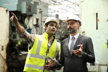Hard-working engineer holding digital tablet in hands while working in manufacturing plant, profile...