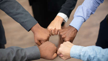 United coworkers standing with their hands together in modern office, celebrating victory, teambuilding and unityの写真素材