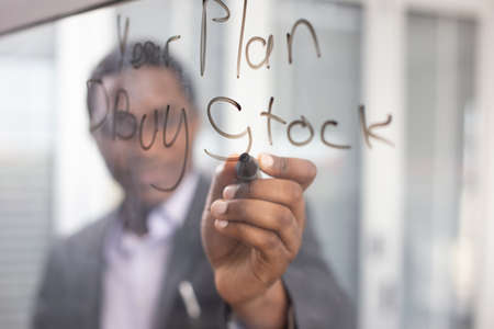 African American young man writing note on a transparent wipe board and thinking of a solution for him work-related problems, Colleagues Having A Business Meetingの写真素材