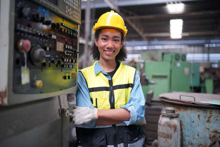 Female apprentice in metal working factory, Portrait of working female industry technical worker or engineer woman working in an industrial manufacturing factory company.の写真素材
