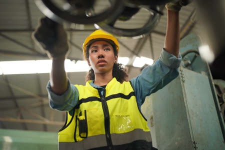 Female apprentice in metal working factory, Portrait of working female industry technical worker or engineer woman working in an industrial manufacturing factory company.の写真素材