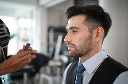 Professional actor preparation before shoot. Handsome young man applying by professional make up of visagist. Male makeupの写真素材