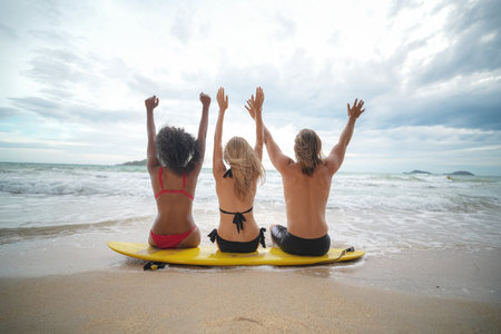 Young mixed race women and a Caucasian women and man enjoying their time at the beach with their friends, holding surfboardsの写真素材