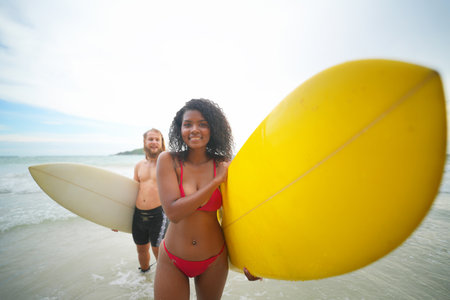 Happy couple surfing together on beach with surfing board in Pattaya, Thailand.の写真素材