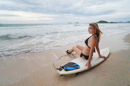 Sexy women poses with surfboard at the beach