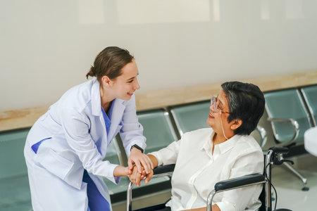Friendly female doctor tries to support patient, holds her handsの写真素材