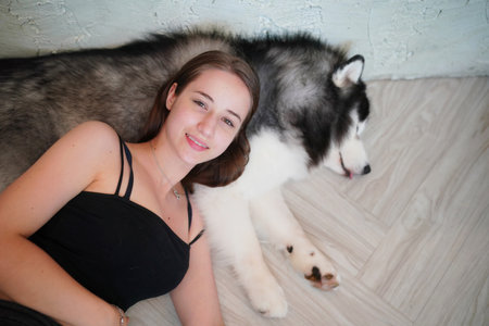 Beautiful young woman playing with a puppy. woman relaxing on floor with dog lying next to herの写真素材