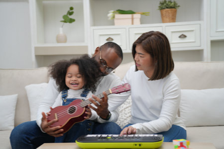 Shot of joyful parents with their little daughter sitting on floor inside living room in sunny day.. Little girl with special needs enjoy spending time with family.の写真素材