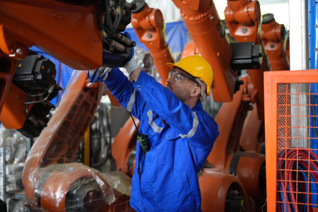 Engineer working in the factory, he is checking the robot arm.の写真素材