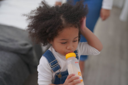 Shot of joyful parents with their little daughter sitting on floor inside living room in sunny day.. Little girl with special needs enjoy spending time with family.の写真素材