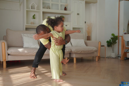 Shot of joyful parents with their little daughter sitting on floor inside living room in sunny day.. Little girl with special needs enjoy spending time with family.の写真素材