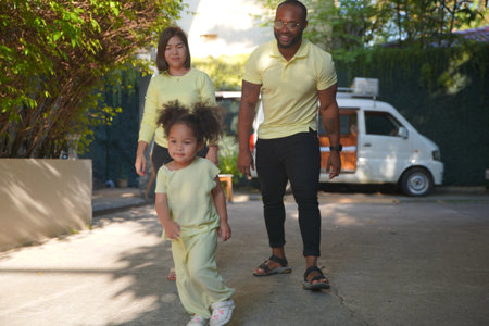 Shot of joyful parents with their little daughter sitting on floor inside living room in sunny day.. Little girl with special needs enjoy spending time with family.の写真素材