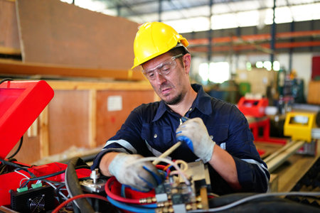 Male technician programs a robot arm with a digital tablet and assembly robot in a factory. Apprentice engineers programming robots in factory.の写真素材