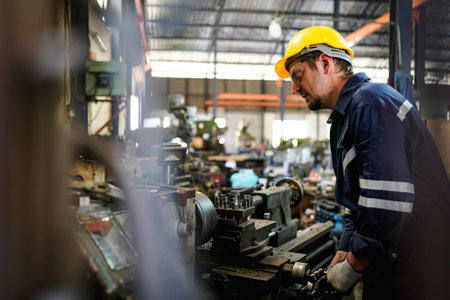Lathe Operators Concentrated on Work. Worker in uniform and helmet works on lathe, factory. Industrial production, metalwork engineering, manufacturing.の写真素材