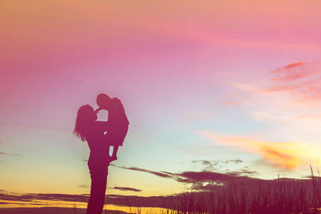 Mother encouraged her son outdoors at sunset, silhouette conceptの写真素材