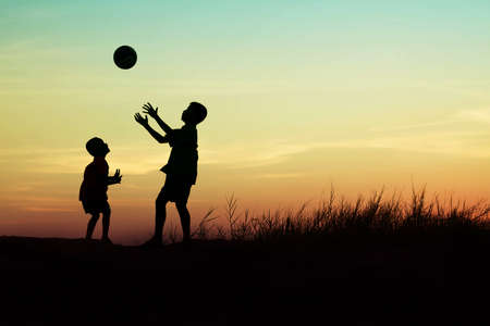 children playing ball on meadow, sunset, summertimeの写真素材