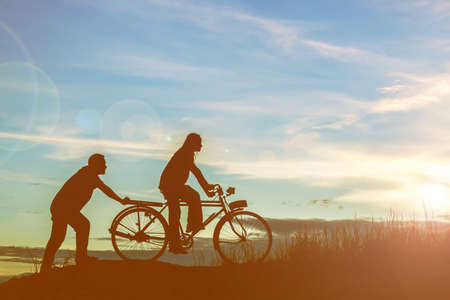 silhouette of couple driving bike happy time sunsetの写真素材